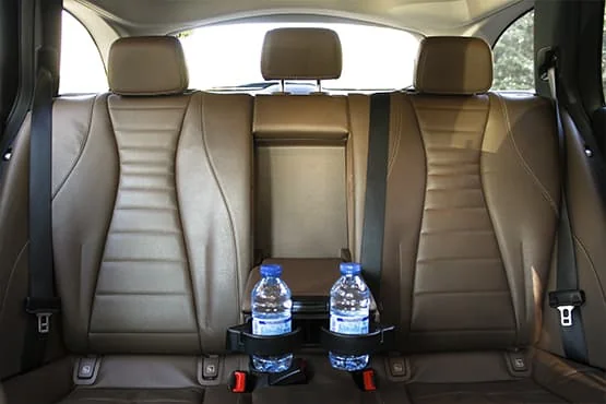 Banquette arrière en cuir beige d’une voiture, avec deux bouteilles d’eau.